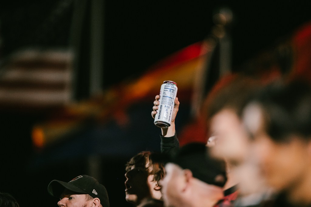 A Rising fans holds up a beer in the crowd.