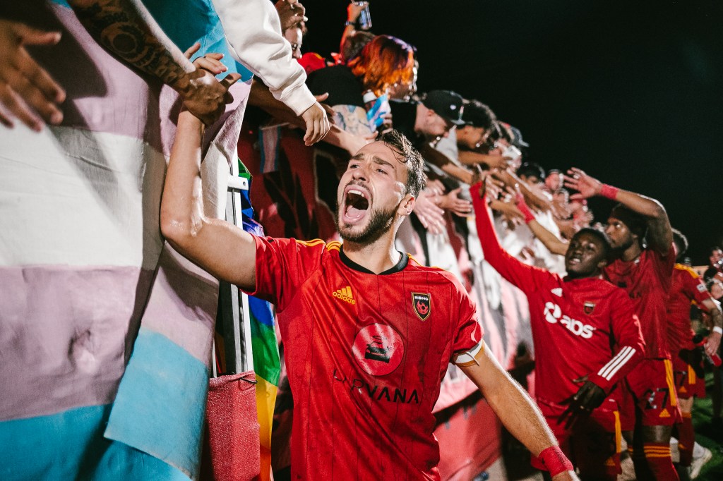 Joe Farrell screams as he giveshigh fives to fans leaning over the South End railings